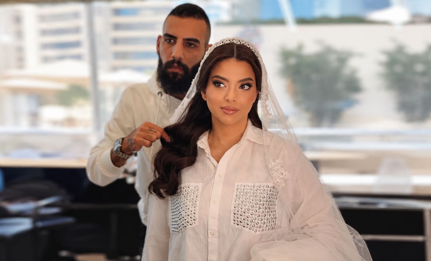 A stylist fixing the final strand of a bride's hair